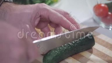 一个人用一把刀在一块分割的木板上切绿色的茄子，用来做蔬菜沙拉。